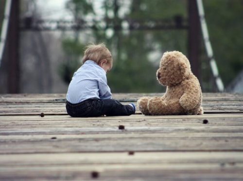 Dreng sidder med en stor bamse, at lære at sidde selv er en af de større milepæle i babys udvikling