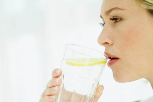 Kvinde drikker varmt vand med citron om morgenen