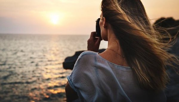 Kvinde tager billede ud over havet