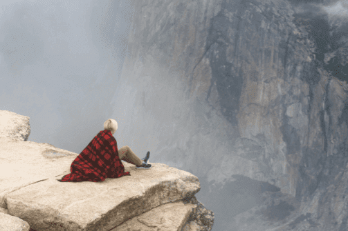 Kvinde der sidder på en sten højt oppe for at overfinde en fobi for højder