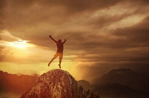 En mand hopper af glæde på toppen af et bjerg