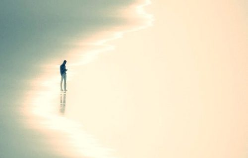 Mand går alene på strand og oplever postmoderne ensomhed