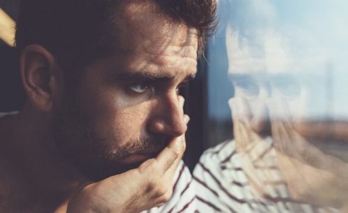 Trist mand der kigger ud i gennem et vindue