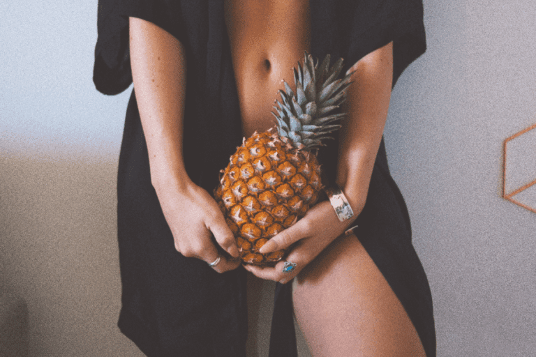 Kvinde holder ananas foran underliv