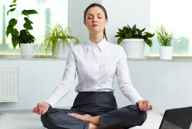 Kvinde mediterer i rum med planter