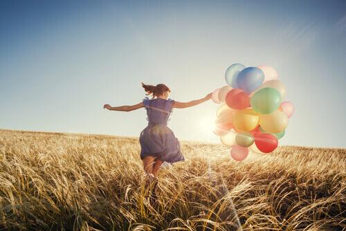 Glad kvinde løber på mark med balloner