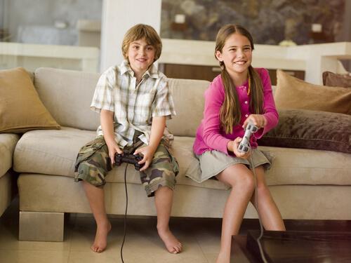 Børn sidder på sofa og spiller videospil