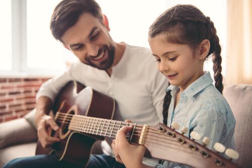 Pigen hjælper med at spille på guitar