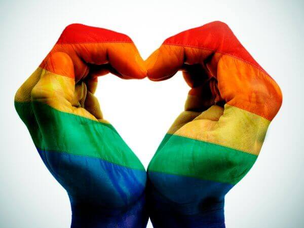 Hænder danner hjerte med regnbueflag