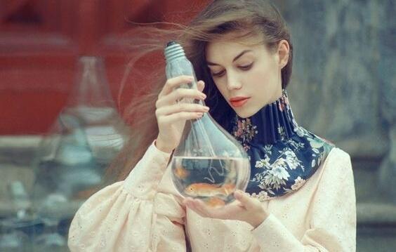 kvinde med en kolbe med væske og guldfisk