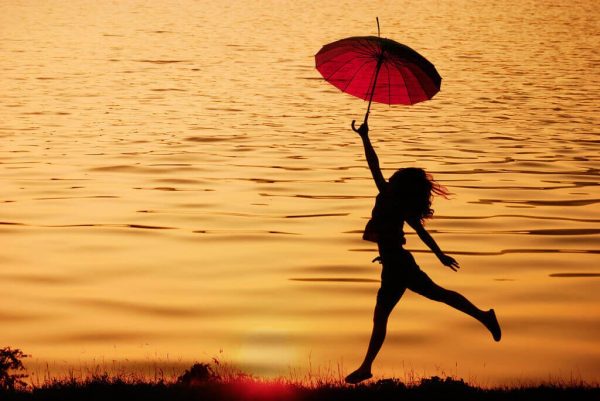 Kvinde, der hopper med paraply, har stor indre motivation