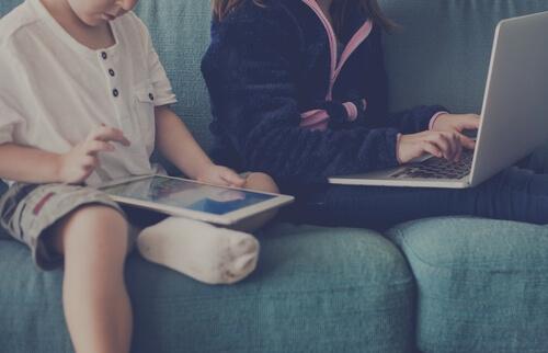 Børn på sofa med teknologi