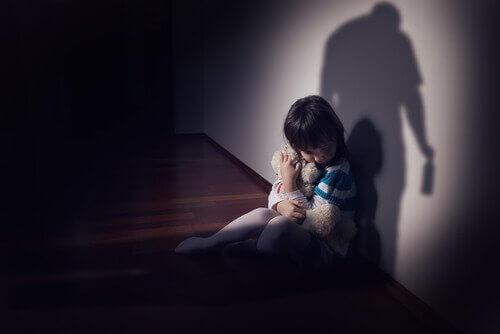 Trist barn, der holder sin bamse af frygt for sin forælder