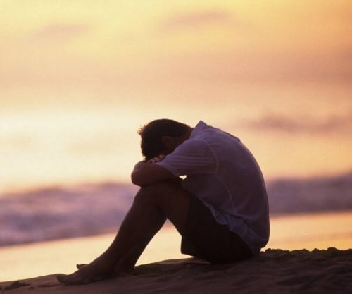 Ulykkelig mand hviler hoved på knæ