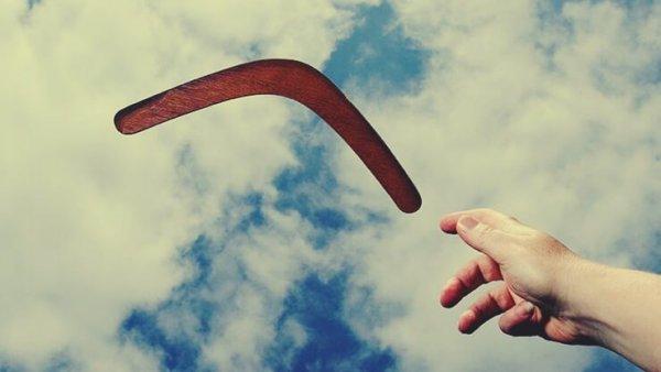 Hånd rækker ud mod boomerang på himmel