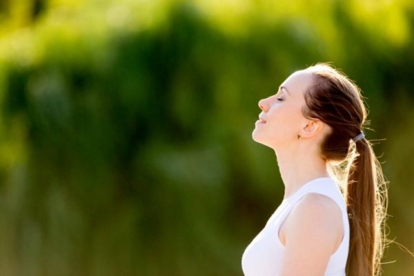 kvinde trækker vejret dybt som et eksempel på mentale øvelser til lykke