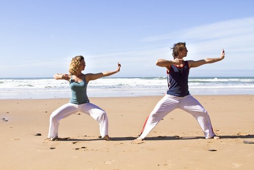 kvinde og mand dyrker qigong på stranden