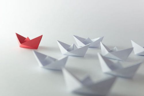 Papirsbåde med rød fører symboliserer lederskab