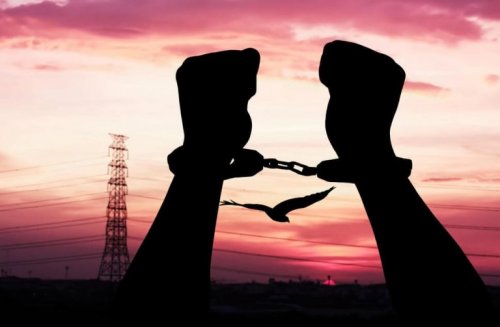 Hænder i lænker foran solnedgang