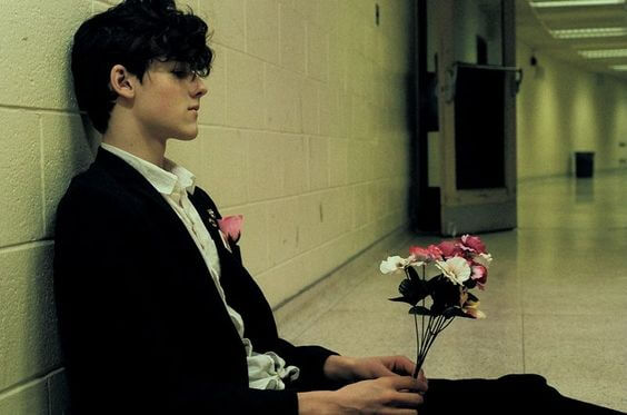 teenage dreng sidder i en gang med blomster, symboliserer når du vil forlade din partner for sent