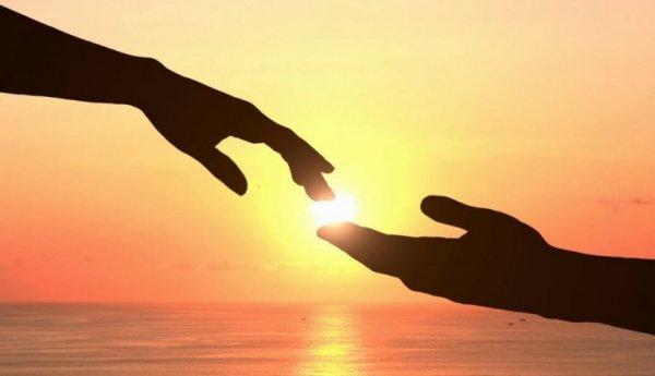 To hænder mødes foran solen