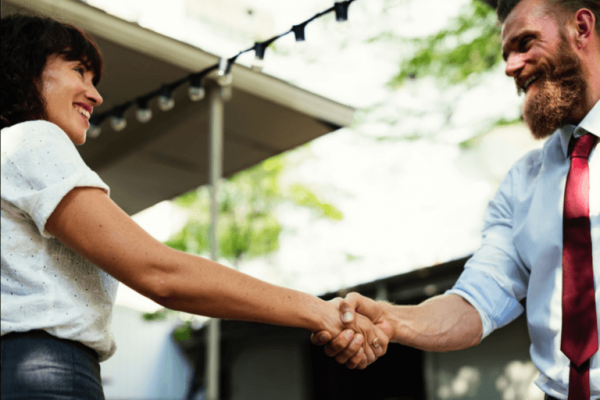 To ansatte giver hånd og smiler