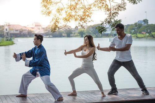 tre mennesker dyrker qigong på en bro