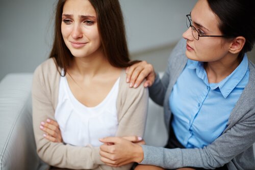 Kvinde trøster anden kvinde, der græder på grund af seksuel tvang