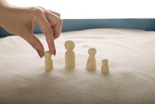 Kvindes hånd rykker på små dukker i sand