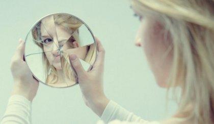 Kvinde ser sig selv i smadret spejl