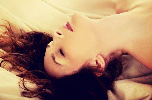 Kvinde i seng nyder onani