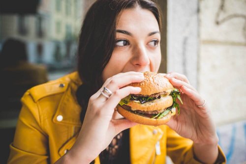 Kvinde spiser en burger, hvilket symboliserer vaner, der sænker din iq