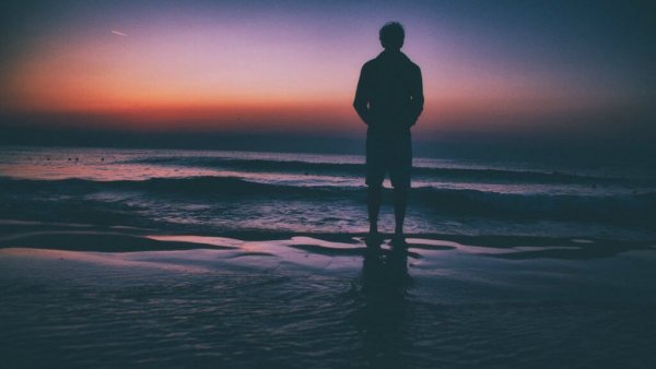 En mand alene på stranden, der tænker på sine barndomserfaringer