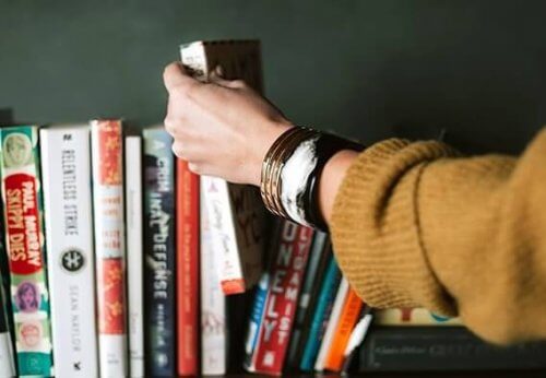 En hånd vælger en bog fra en hylde