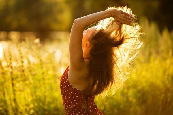 Kvinde på eng leger med sit hår og nyder friheder