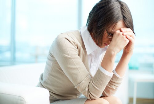 En stresset kvinde på arbejdspladsen tager sig til hoved