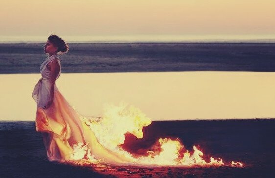 Kvinde på strand med ild i kjole symboliserer en selvdestruktiv person