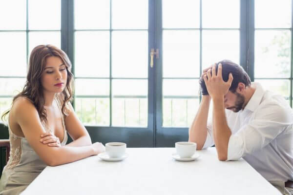 Mand og kvinde er frustrerede ved bord med kaffekopper