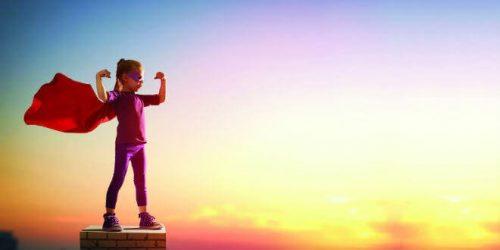 Pige klædt i superheltekostume på toppen af bygning