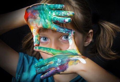 Pige med maling på hænderne danner firkant med fingre foran øjne