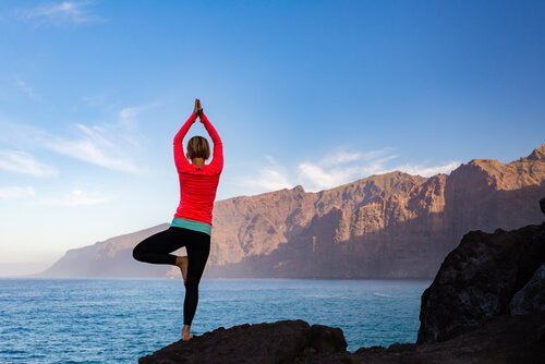 Kvinde laver yogaøvelser ved bjerge og sø