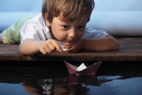Dreng leger med papirsbåd