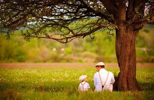 Far og søn taler sammen under træ