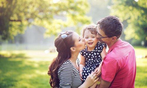 Forældre kysser datter på kinderne