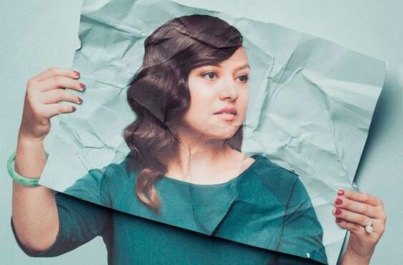 Kvinde med krøllet billede af sig selv foran ansigtet