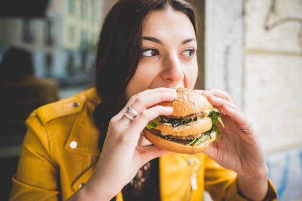 Kvinde spiser stor burger