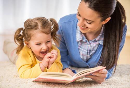 Mor og datter griner over bog, da det skal være sjovt for barnet at lære at læse