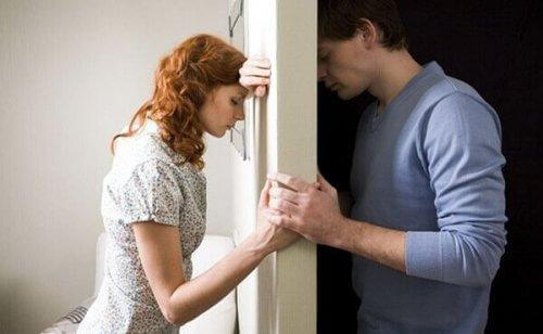 Mand og kvinde på hver sin side af væg holder stadig i hånd
