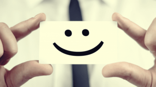 Smiley på papir holdes af fire fingre