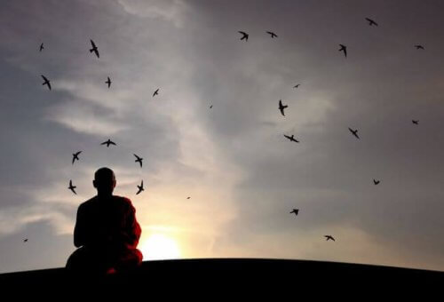 Munk mediterer foran himmel med fugle